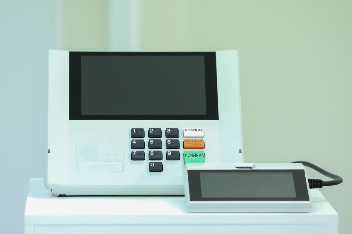 Urna eletrônica brasileira modelo UE2020, com teclado numérico e tela, sobre uma mesa branca