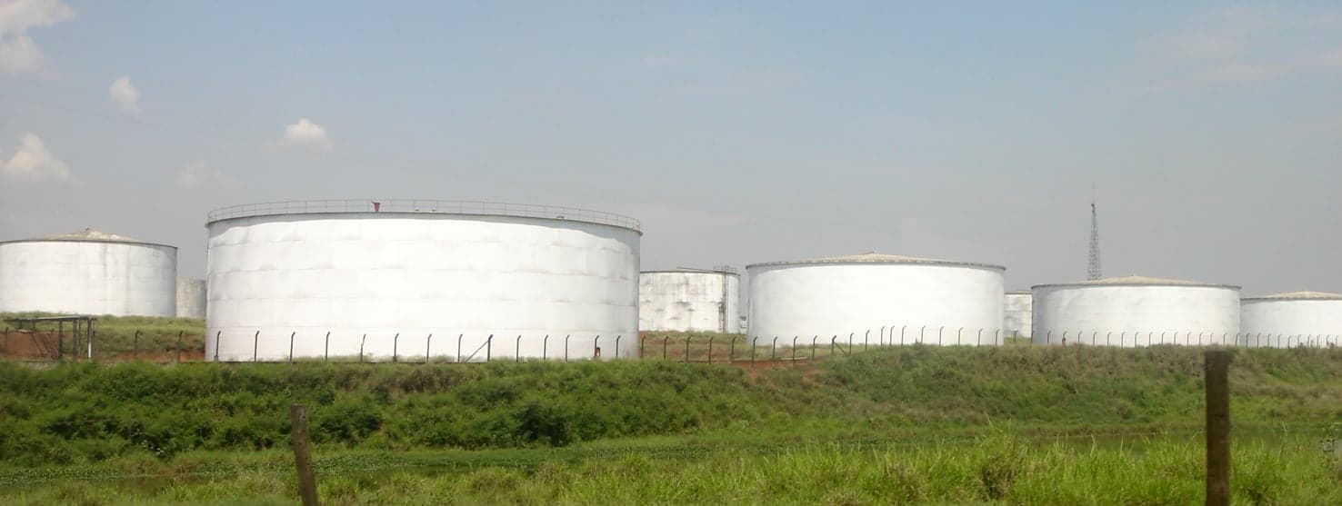 Grandes tanques brancos de armazenamento de etanol atrás de um gramado