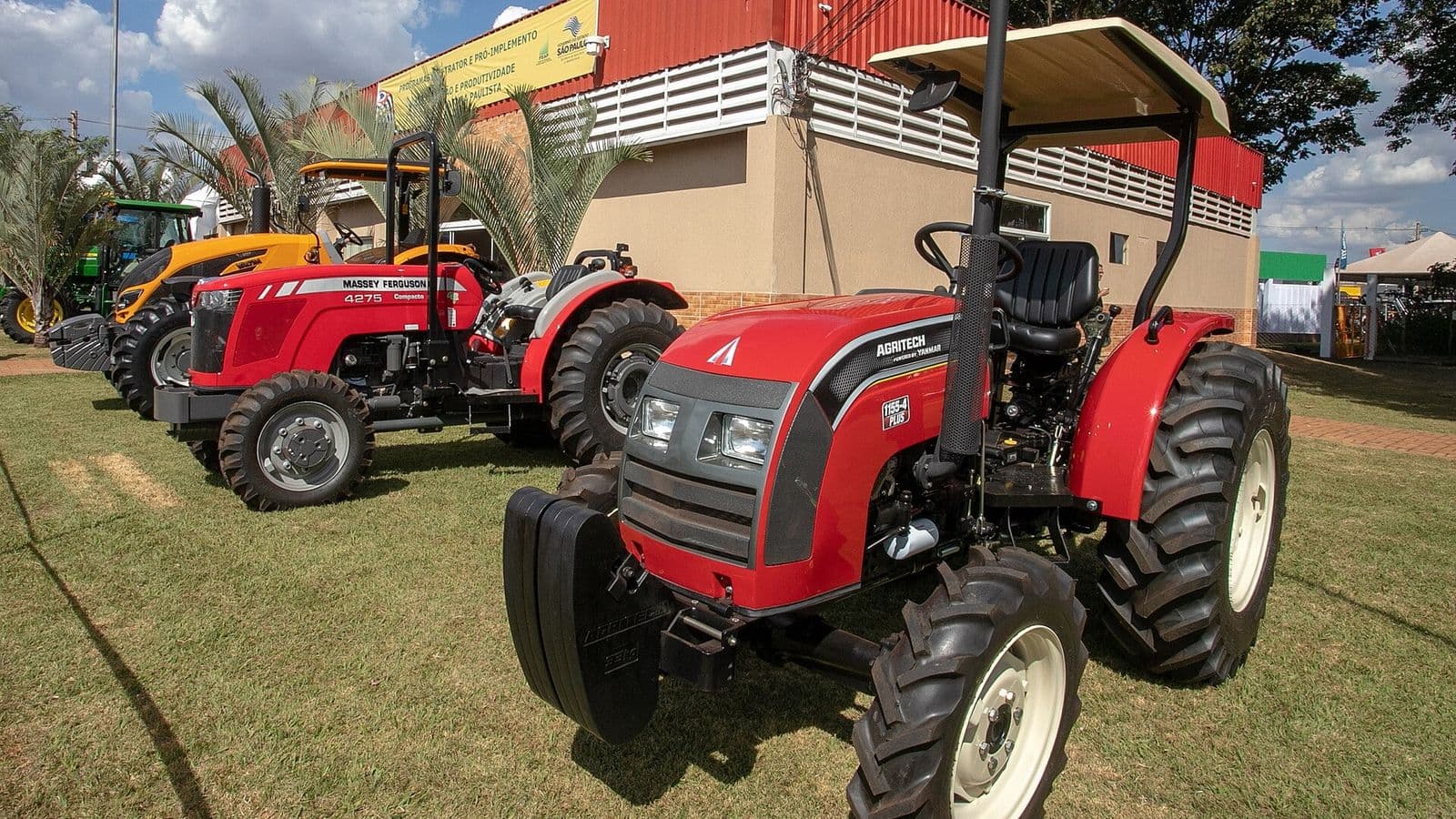 Tratores vermelhos estacionados no gramado de uma feira agrícola